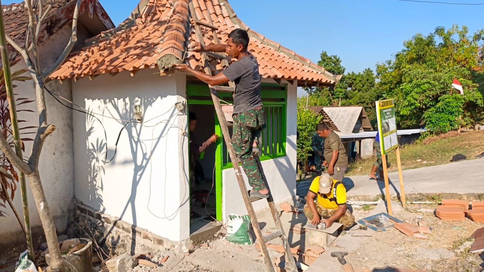Tunjukkan Kepiawaian di Ketinggian, Sertu Edi Anggota Satgas TMMD 129 Lincah Panjat Atap Rampungkan Pemasangan dan Finishing Pos Kamling